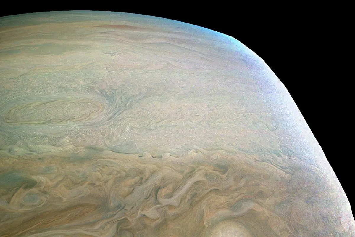 Swirling cream, brown and blue cloud bands at the edge of Jupiter