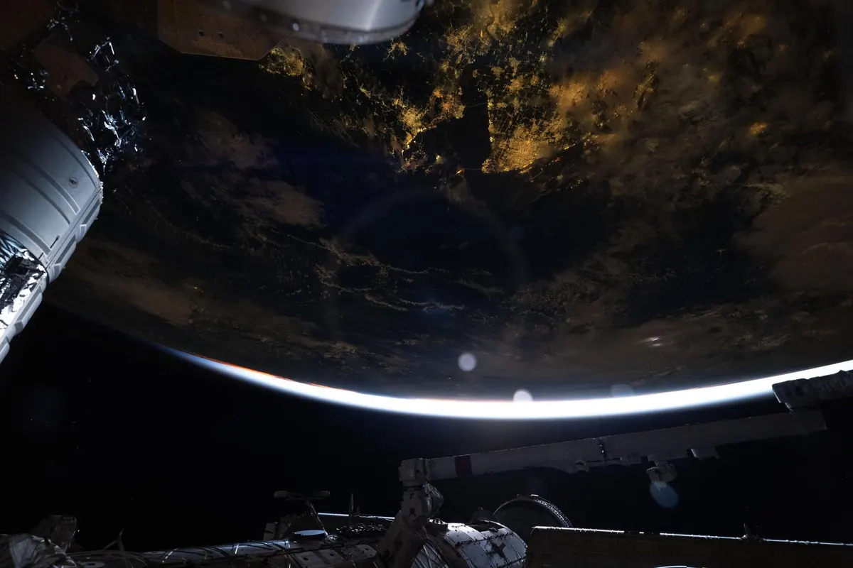 City lights on Earth at night seen from the International Space Station, with station hardware in the foreground