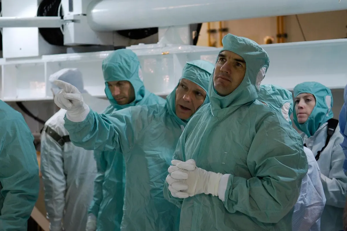 Astronauts in clean-room suits examining the Columbus laboratory module in the payload bay of Space Shuttle Atlantis
