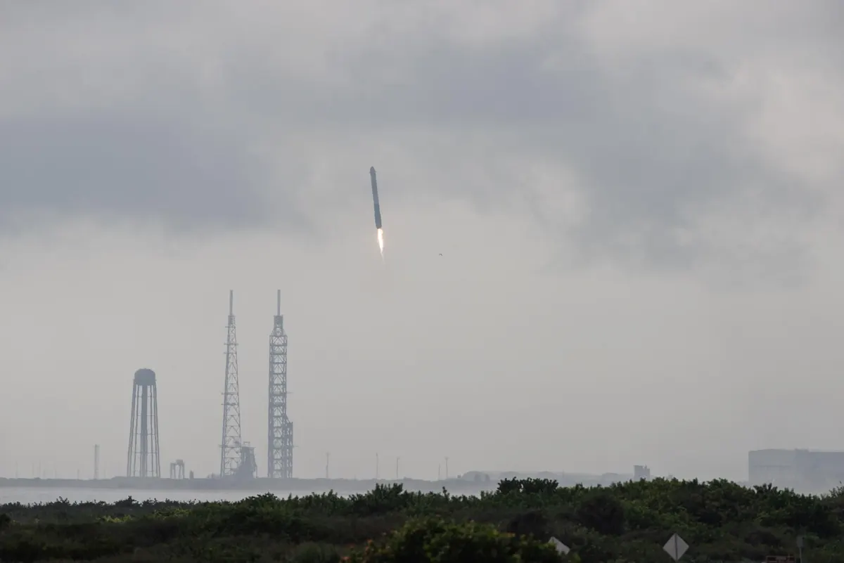 A Falcon Heavy rocket lifting off in the distance above the Florida coast