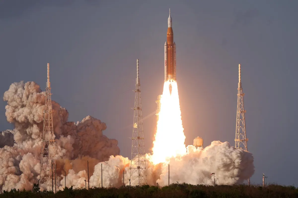 The Space Launch System rocket rising on a column of flame and smoke